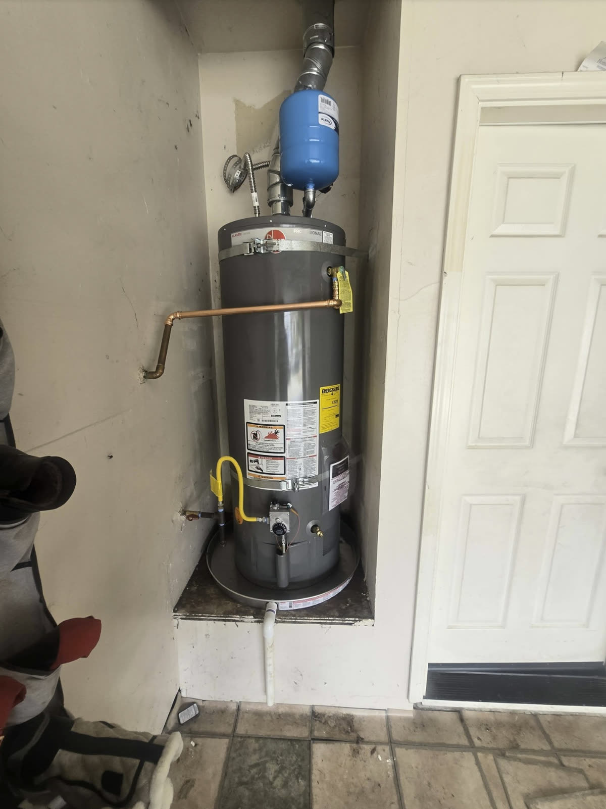 Gas water heater installed by Laird’s Plumbing & Drain with a thermal expansion tank, copper supply lines and a yellow flexible gas connector