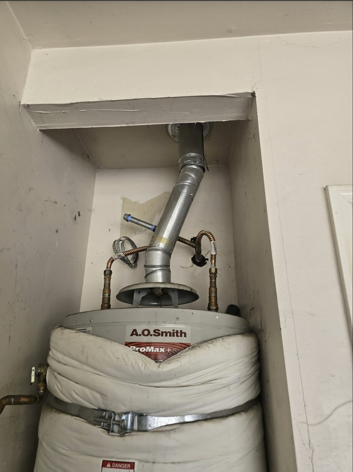 Water heater flue venting and flexible connectors on an A.O. Smith unit installed in a tight interior closet